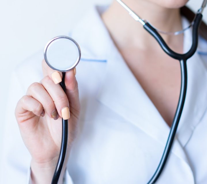 a woman in a white shirt holding a stethoscope {{brizy_dc_image_alt imageSrc=