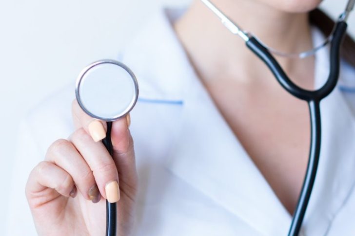 a woman in a white shirt holding a stethoscope